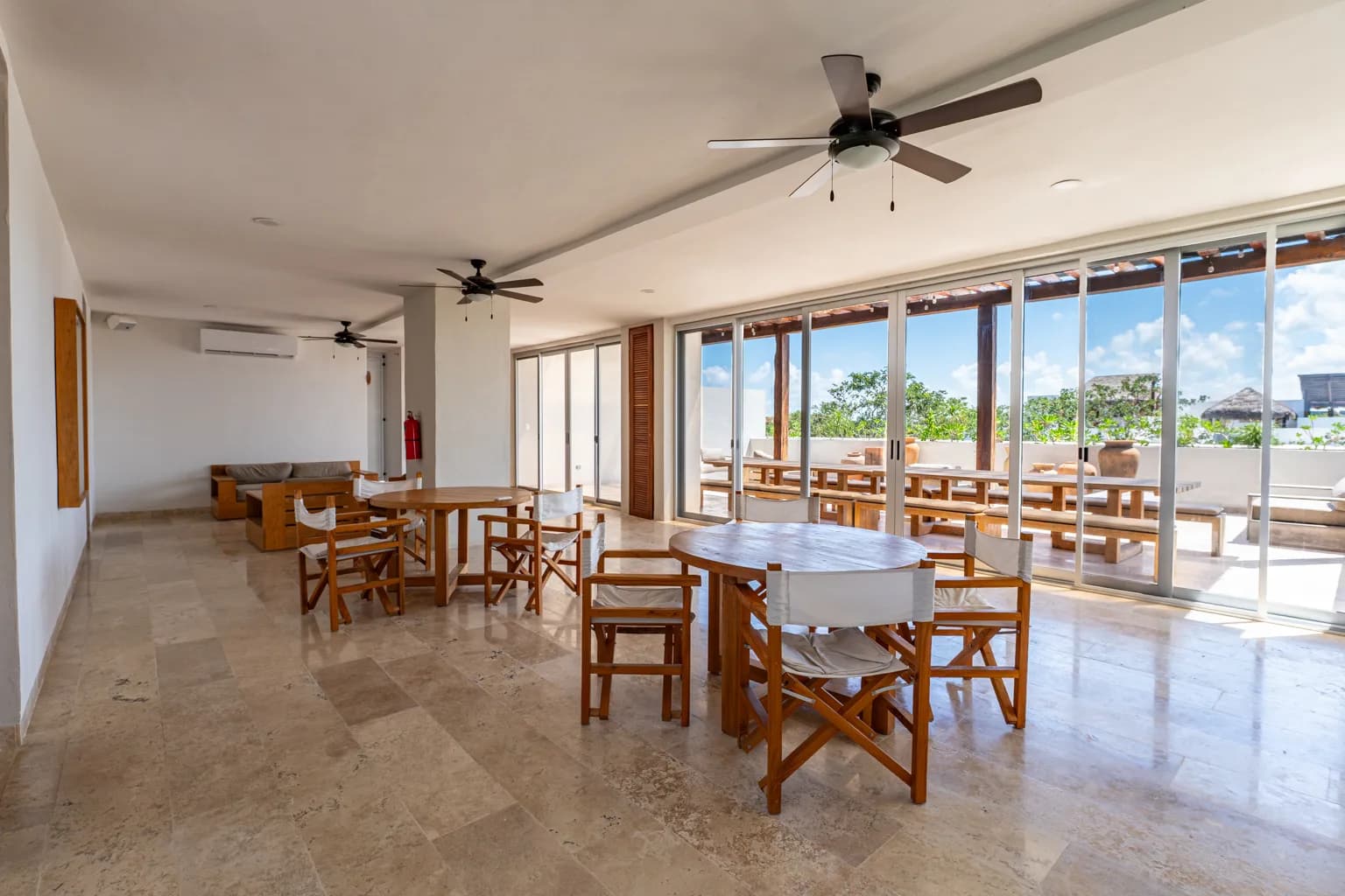 Salón con mesas de madera y ventanales hacia el rooftop